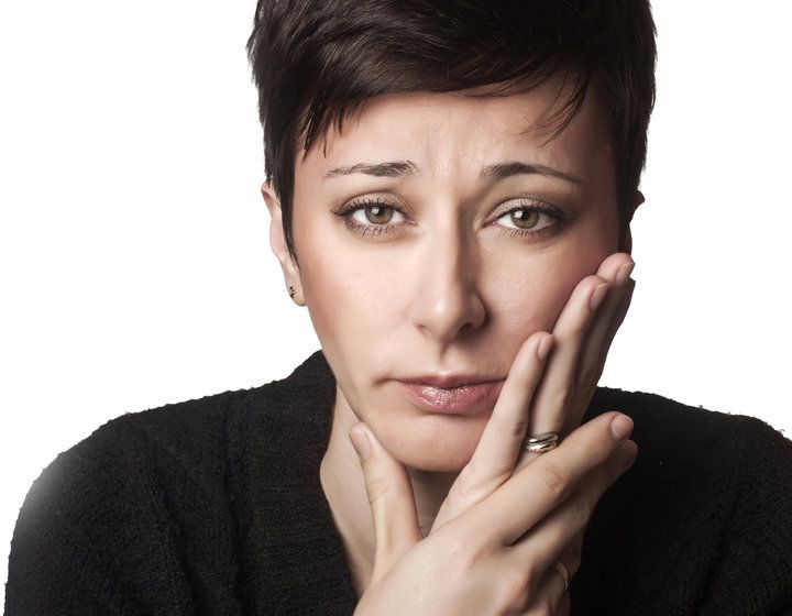 Photo of woman with hands on face in pain
